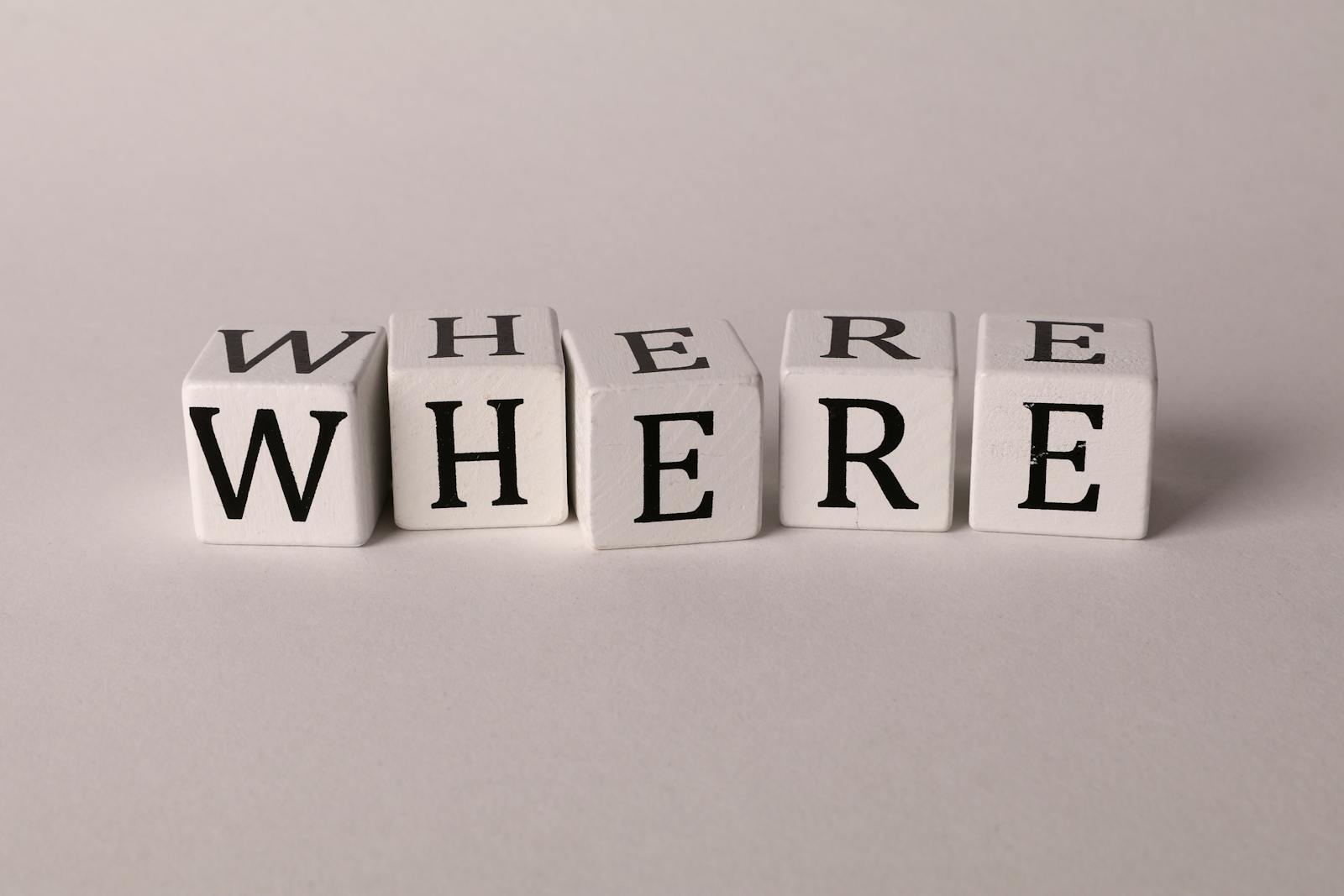 Close-up of white blocks with letters spelling 'WHERE' against a plain background.